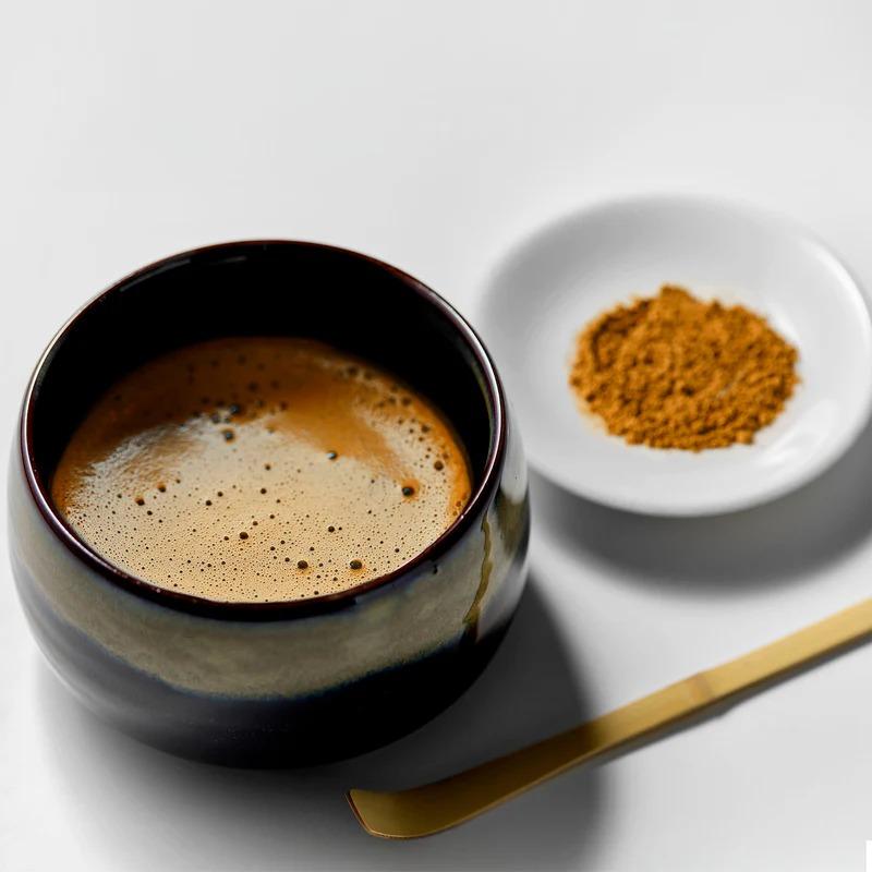 A cup of frothy Hojicha latte next to a small dish of roasted hojicha powder and a bamboo spoon.