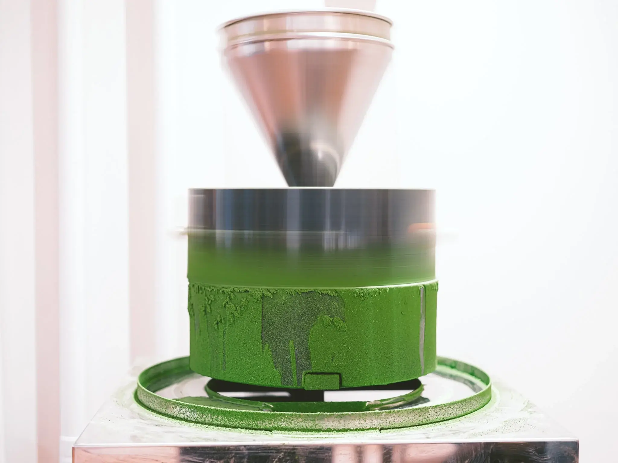 Granite stone mill slowly grinding fresh Tencha leaves into fine stone-ground ceremonial matcha powder.
